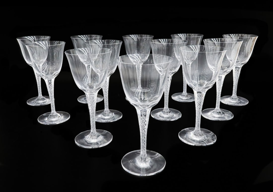 12 Lalique France Crystal Glass Water Goblets in Treves: 12 Lalique France water glass goblets in Treves. Clear facet stems with swirls. Lalique mark to the underside base. Weight: Approx. 5 lb Measurements: Approx. 3.4 inches diameter x 7.25 inches tall
