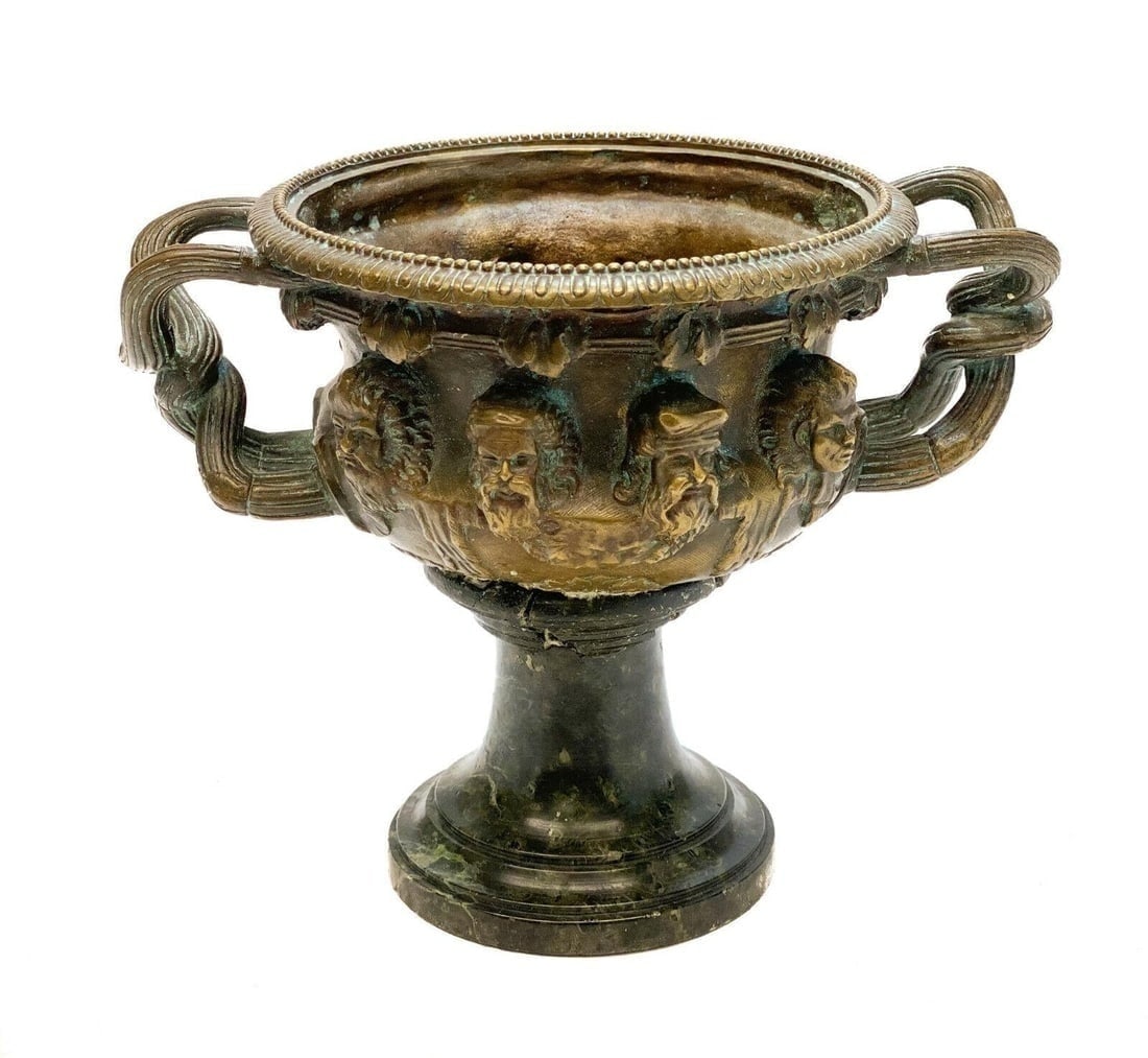 Continental Patinated Bronze and Marble Stem Twin Handled Cup. Early 20th Centur: Continental patinated bronze and marble stem twin handled cup. Early 20th Century. Applied figure heads throughout the exterior of the cup with a dark marble stem. Weight: Approx. 4 lbs Measurements: