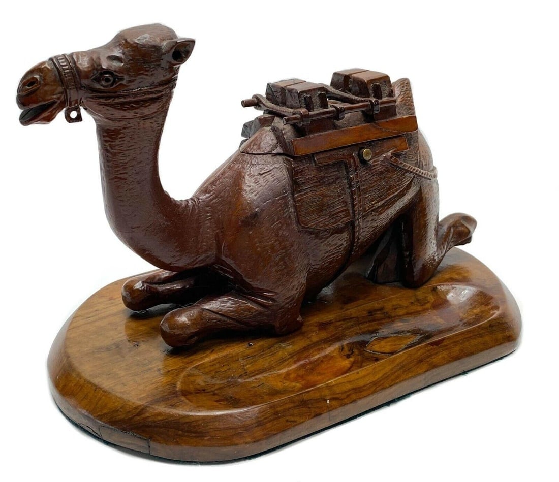 Continental Hand Carved Novelty Ink Stand & Pen Tray: A finely hand carved ink stand modeled as a sitting camel c. early 20th century. The hump opens to revel two glass lined ink wells to the forefront and a carved inset area serving as a pen holder. Mar