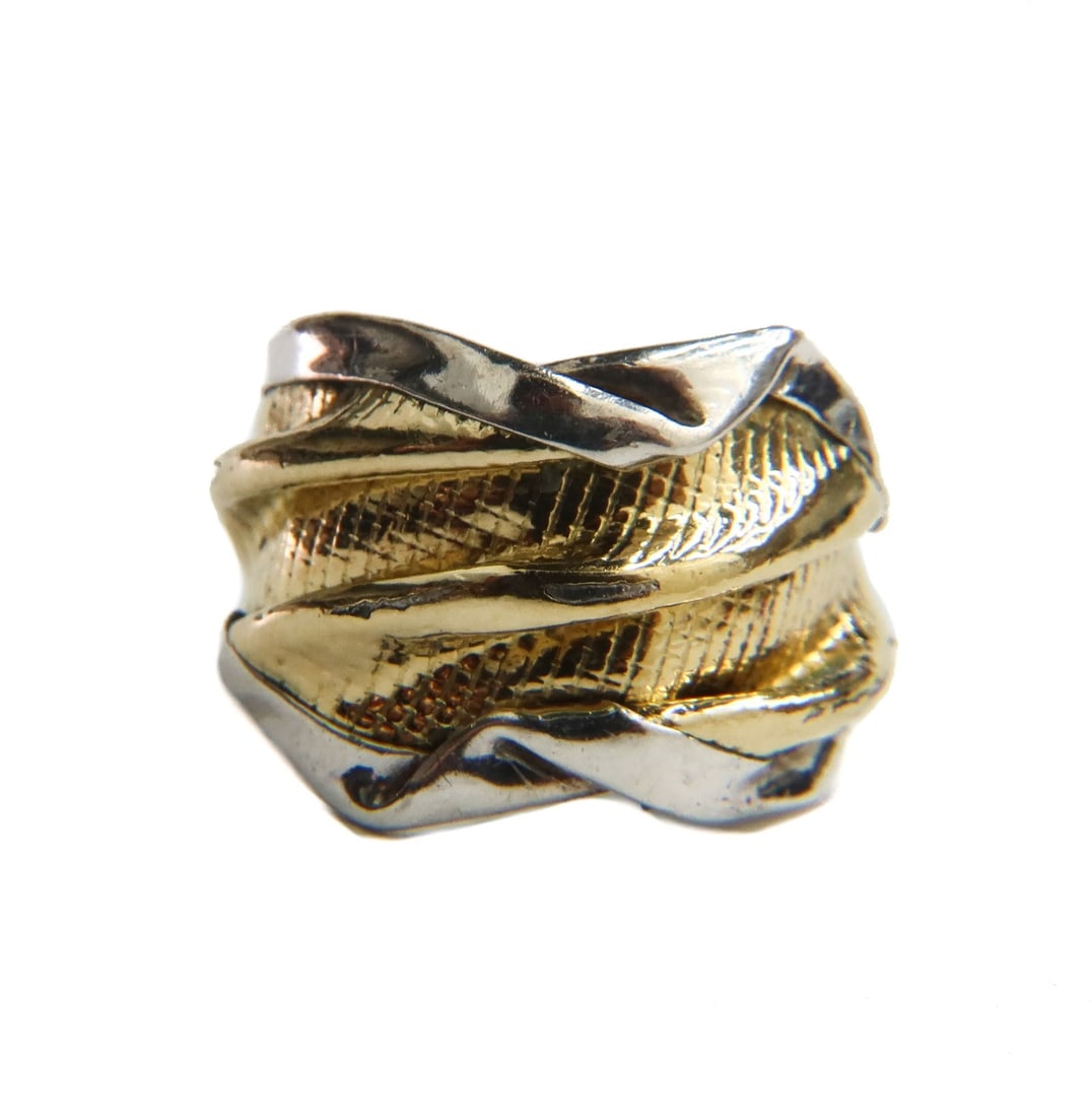 18k Yellow Gold and Sterling Silver Ring Size 7: 18k Yellow Gold and Sterling Silver Ring Size 7. Wrinkled wrapped silver and gold band with cross hatched texture to band. Marked 18k sterling to inner band with an indistinguishable artist mark to We