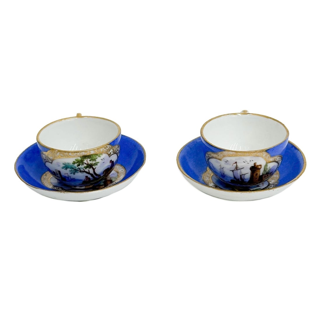 Pair Meissen Germany Hand Painted Miniature Porcelain Cup & Saucers c1900: Pair Meissen Germany Hand Painted Miniature Porcelain Cup & Saucers, circa 1900. A blue ground, each with a scenery panel to center. Underside with Meissen crossed swords mark, each with scratches thr
