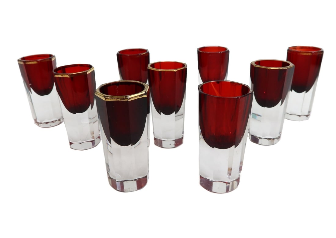 9 Cranberry and Clear Gilt Rim Octagonal Lobed Shot Glasses: 9 cranberry and clear gilt rim octagonal lobed shot glasses. Cranberry red bowl with clear base. Gilt to rim. Unmarked. Weight: Approx. 1 lb Measurements: Approx.1.25 inches diameter x 2.75 inches tal