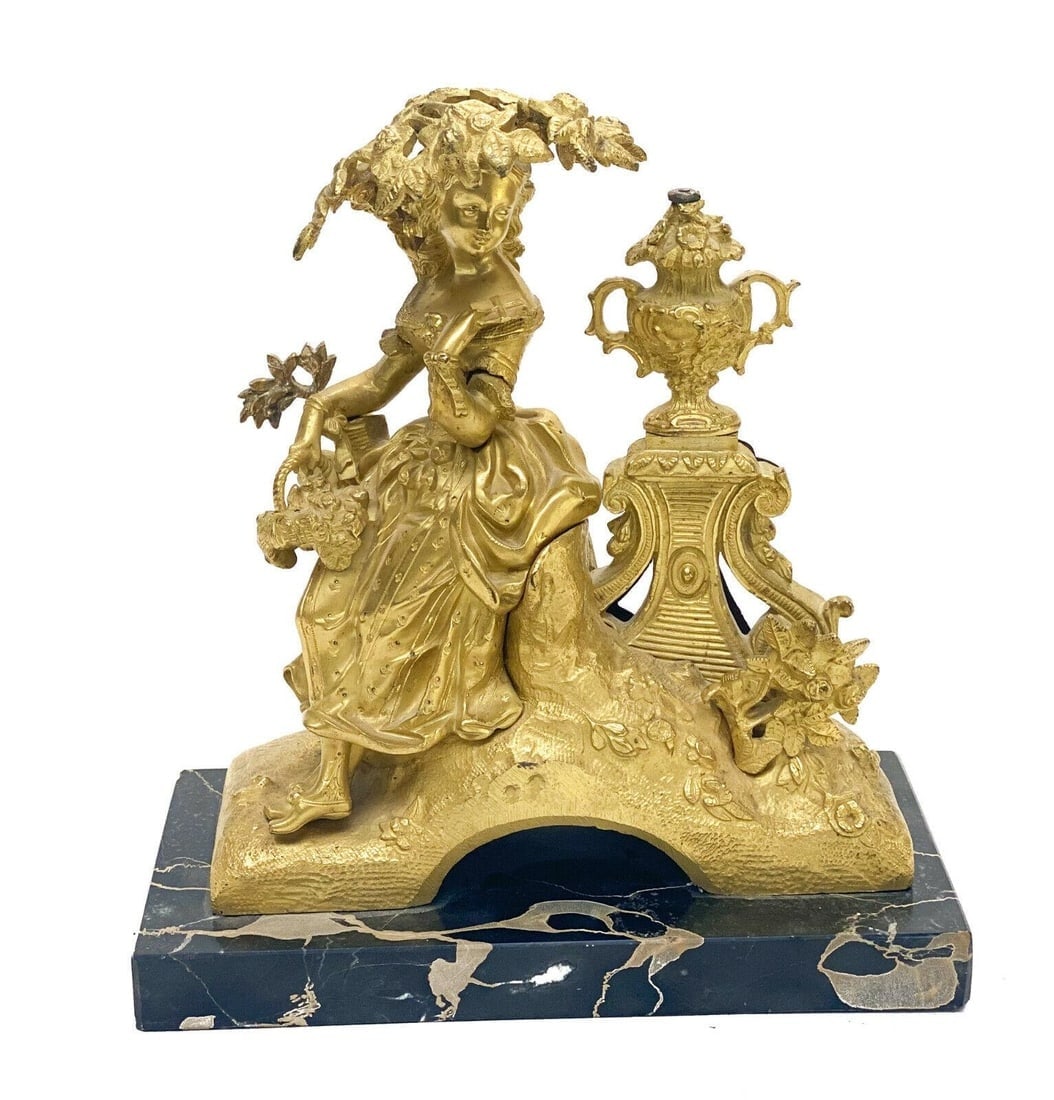 French Gilt Bronze Figural Sculpture of a Beauty on Marble Base, 19th Century: French gilt bronze sculpture of a beauty, 19th Century. The sculpture depicts a beauty sitting underneath a tree and holding a basket of flowers. A side table with an urn behind her. Mounted to a blac