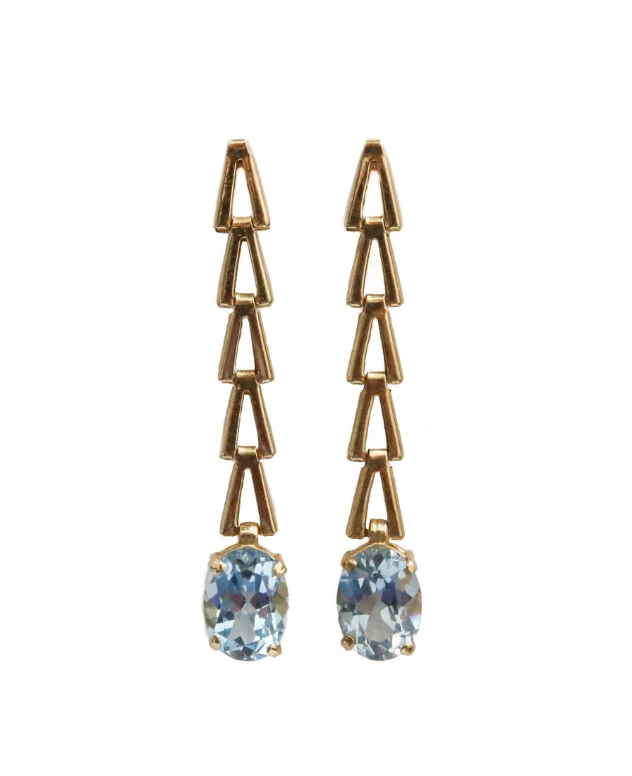 14k Yellow Gold and Blue Topaz Triangular Dangle Earrings: 14k yellow gold and blue topaz triangular dangle earrings. Oval cut topaz measuring approx. 8.04mm x 6.15mm x 8.04mm. Marked 14k. Weight: Approx. 2.52 grams Measurements: Approx. 1.625 inches length C