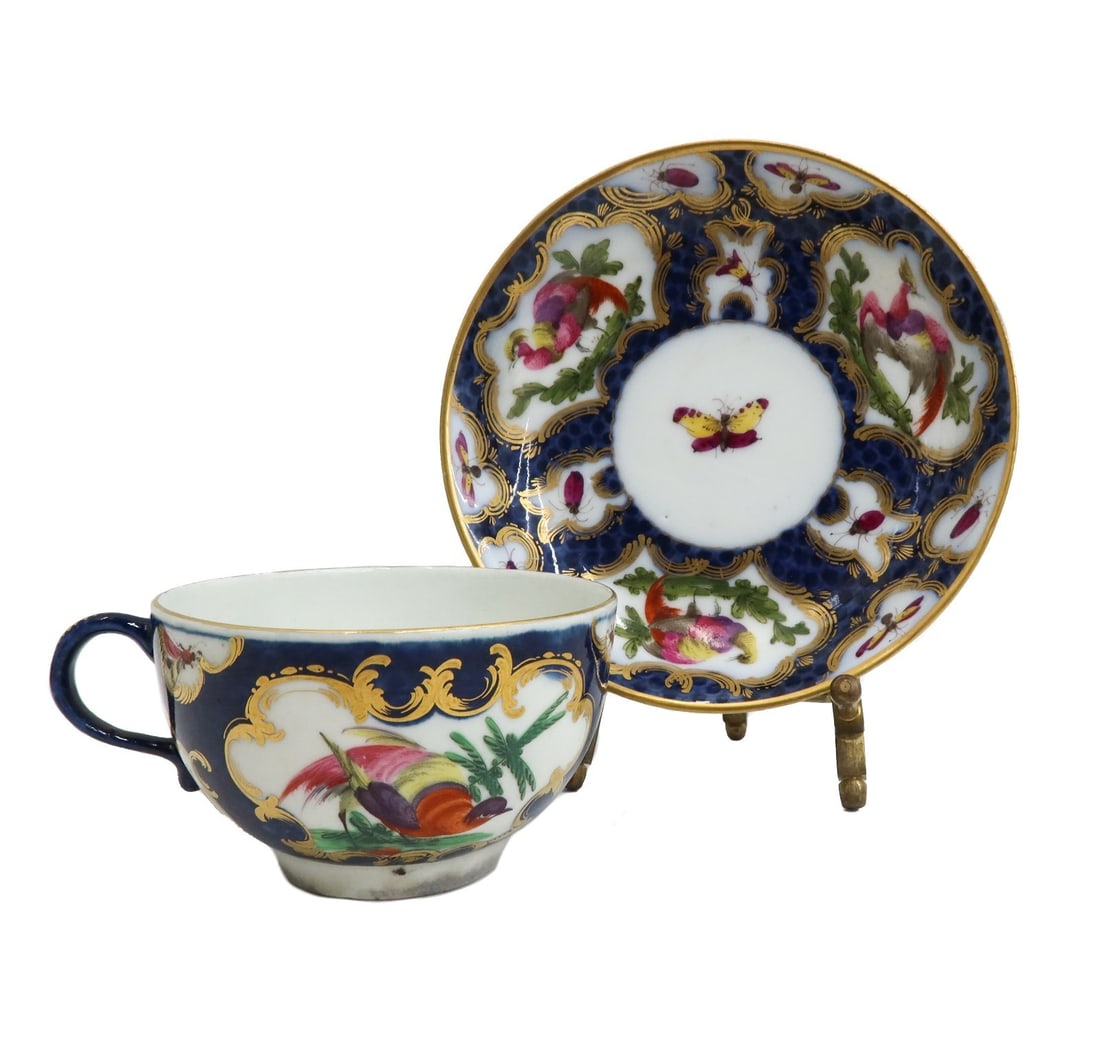 Royal Worcester England Porcelain Cup and Saucer Exotic Birds circa 1770: Royal Worcester England porcelain cup and saucer exotic birds, circa 1770. Blue scale with gilt accents and hand painted exotic birds and butterflies throughout. Royal Worcester blue fret mark to unde
