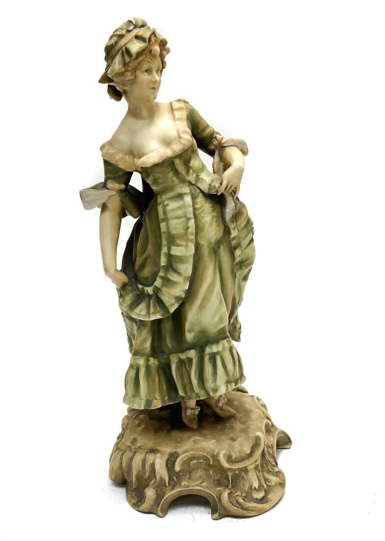 Austrian Porcelain Sculpture of a Maiden in Green Dress, circa 1900. Signed: Austrian porcelain sculpture of a maiden, circa 1900. The sculpture depicts a maiden in green garbs standing on a foliate scroll base. Marked to the verso with an intertwined "PD" signature. Weight Ap