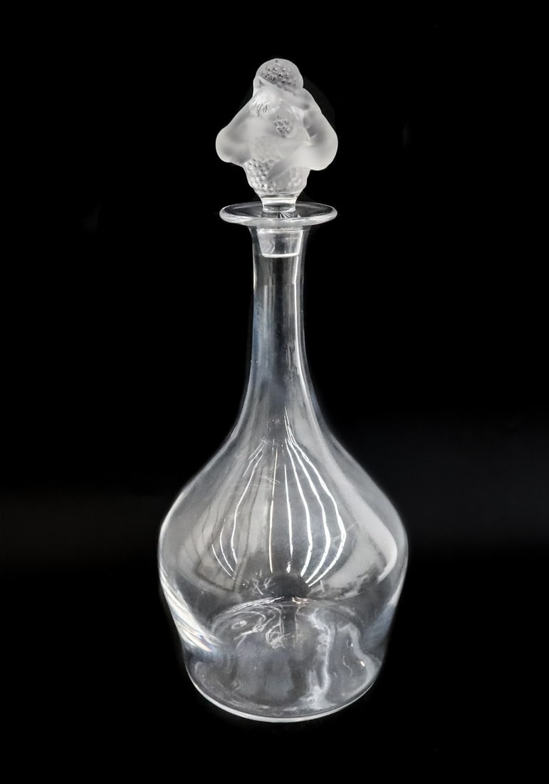 Lalique France Crystal Glass Decanter in Roxane Signed: Lalique France crystal glass decanter in Roxane, Signed. 2 frosted nude figures embracing grapes or flowers to stopper. Marked Lalique France to underside. Weight: Approx. 4 lbs Measurements: Approx. 