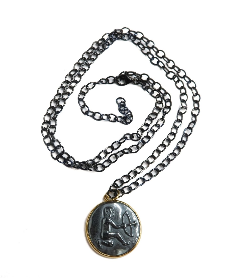 Syna 18k Yellow Gold and Hematite Sagittarius Pendant Necklace: Syna 18k Yellow Gold and Carved Hematite Sagittarius Pendant Necklace. The center of the pendant depicts a man with an arrow depicting the Sagittarius sign. Marked "Syna 750" to edge. Weight: Approx. 
