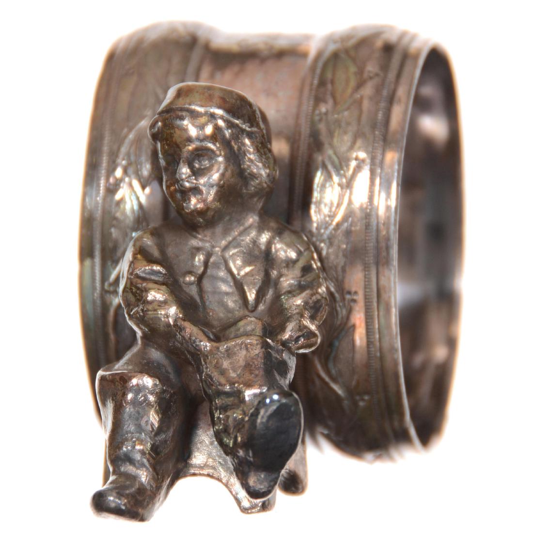 Victorian Silverplate Napkin Ring: Victorian Silverplate Napkin Ring 1.75" X 3" - No Maker's Mark Visible - Young Boy on Stool Pulling on Boot - Engraved "Sailed 'Wey' "
