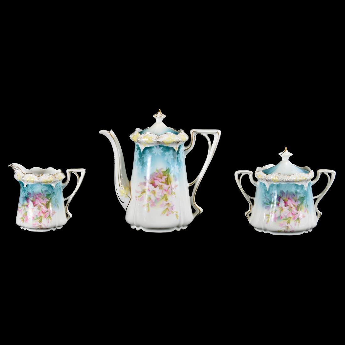 Three Piece Tea Set - Unmarked Prussia 6.75" Pot: Three Piece Tea Set- Unmarked Prussia - 6.75" Pot - Stippled Mold - Blue and White Tones with Pink Lily Decor - Pot, Matching Creamer and Sugar - Point of Each Finial Has Nick