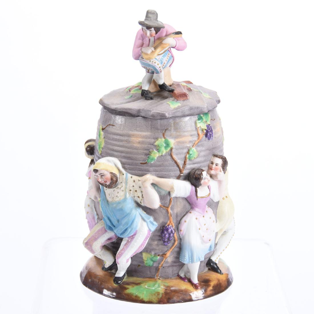Bisque Porcelain Covered Jar 9": Bisque Porcelain Covered Jar - 9" - Embossed Revelers Dancing Around Barrel with Figural Finial of Man Playing Fiddle - Marked "S&S" - Restoration Evident on interior