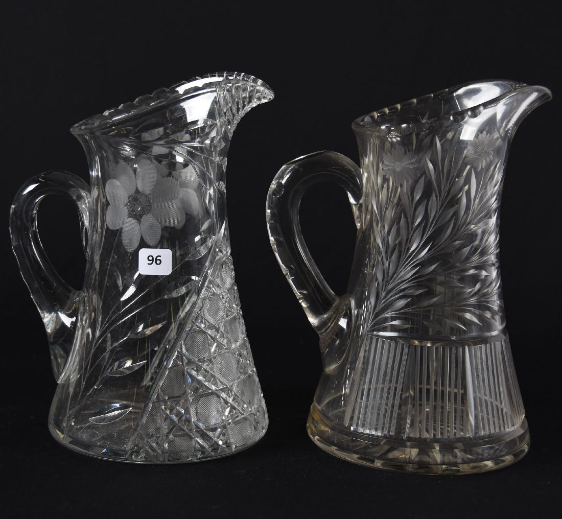 (2) Water Pitchers, American Brilliant Cut Glass: (2) American Brilliant Cut Glass Water Pitchers; (1) 10" Harvard and Daisy Motif; (1) 10" Daisy and Vertical Stripe Panel Motif, Handle/Body Crack