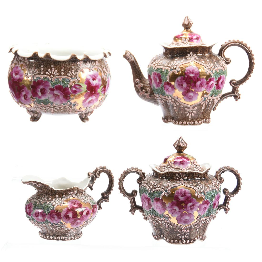 Four Piece Unmarked Nippon Style Tea Set: Four Piece Unmarked Nippon Style Tea Set, Brown Mottled Background with Green and Gold Center Section with Pink Rose Decor; (1) 6.5" Teapot, Rim Chip and Spout Damage; (1) Creamer, Handle Chip; (1) Su