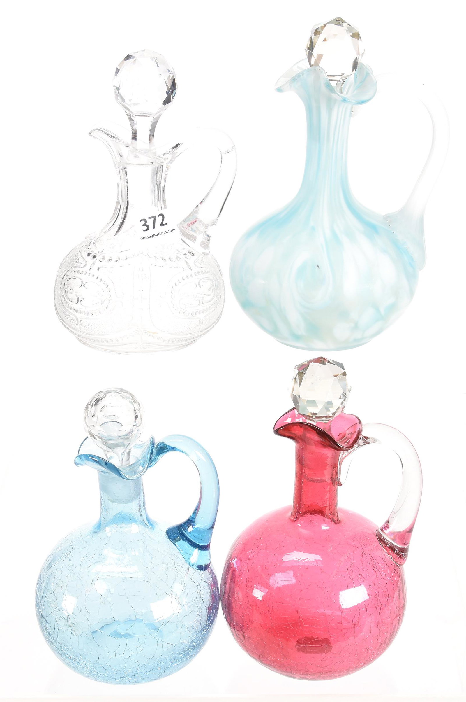 (4) Cruets, various colors and patterns: (4) Cruets, various colors and patterns various sizes Includes: (1) 6.5" Blue & white spatter, frosted ribbed handle; (1) 6.25" Cranberry crackle; (1) 5.75" Blue crackle; (1) 5.75" Clear Locket on Cha