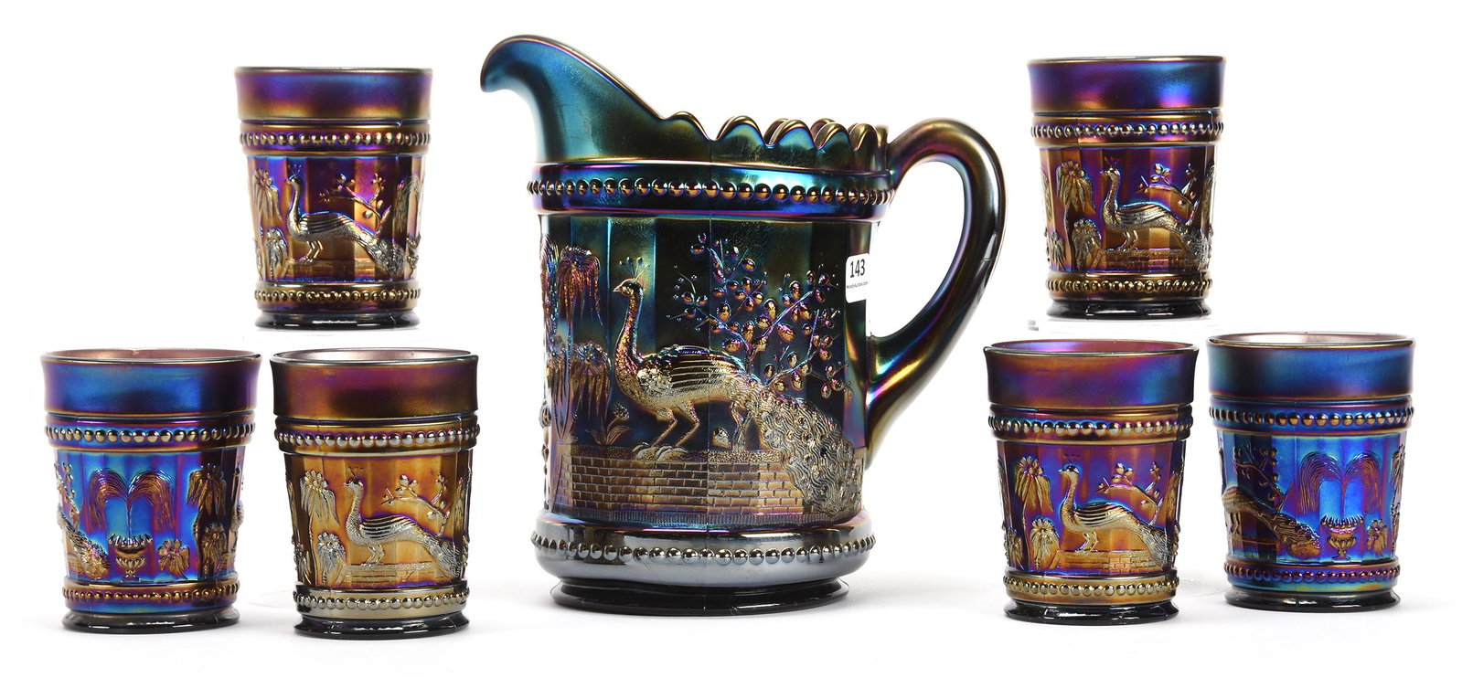 Carnival Glass Water Set, Peacock at The Fountain: Carnival glass water set, Peacock at the Fountain; 8.75", 4" Purple by Northwood - (1) 8.75" Water pitcher with (6) 4" tumblers - Nice Set!; Don Anderson Collection, Kansas. UPDATED 12-5-19: There is 