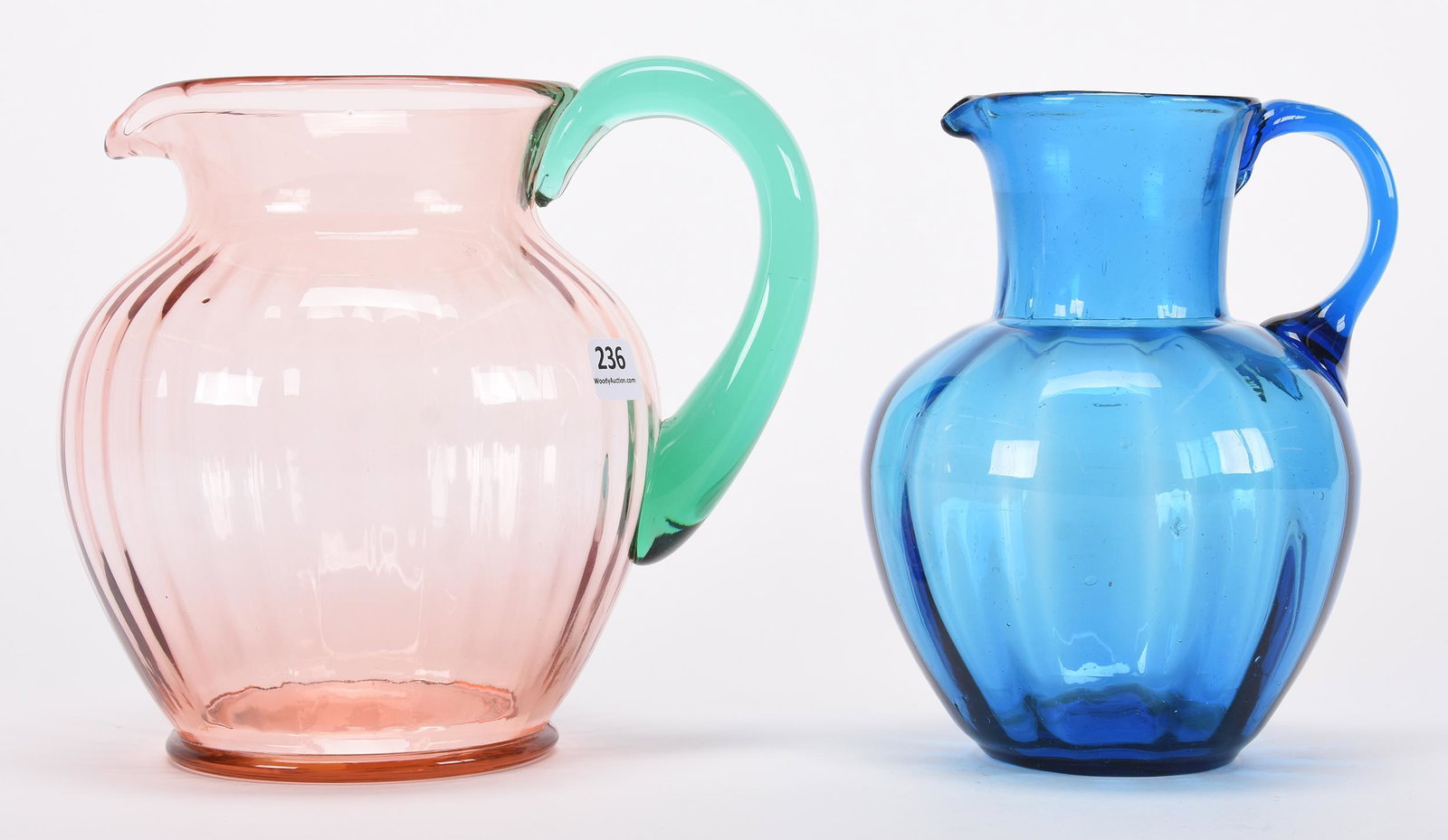 (2) art glass pitchers: (2) art glass pitchers; 7.75", 7.25" ; (1) 7.75", pink with applied solid green handle; (1) solid blue ; Hopper Collection, Kansas