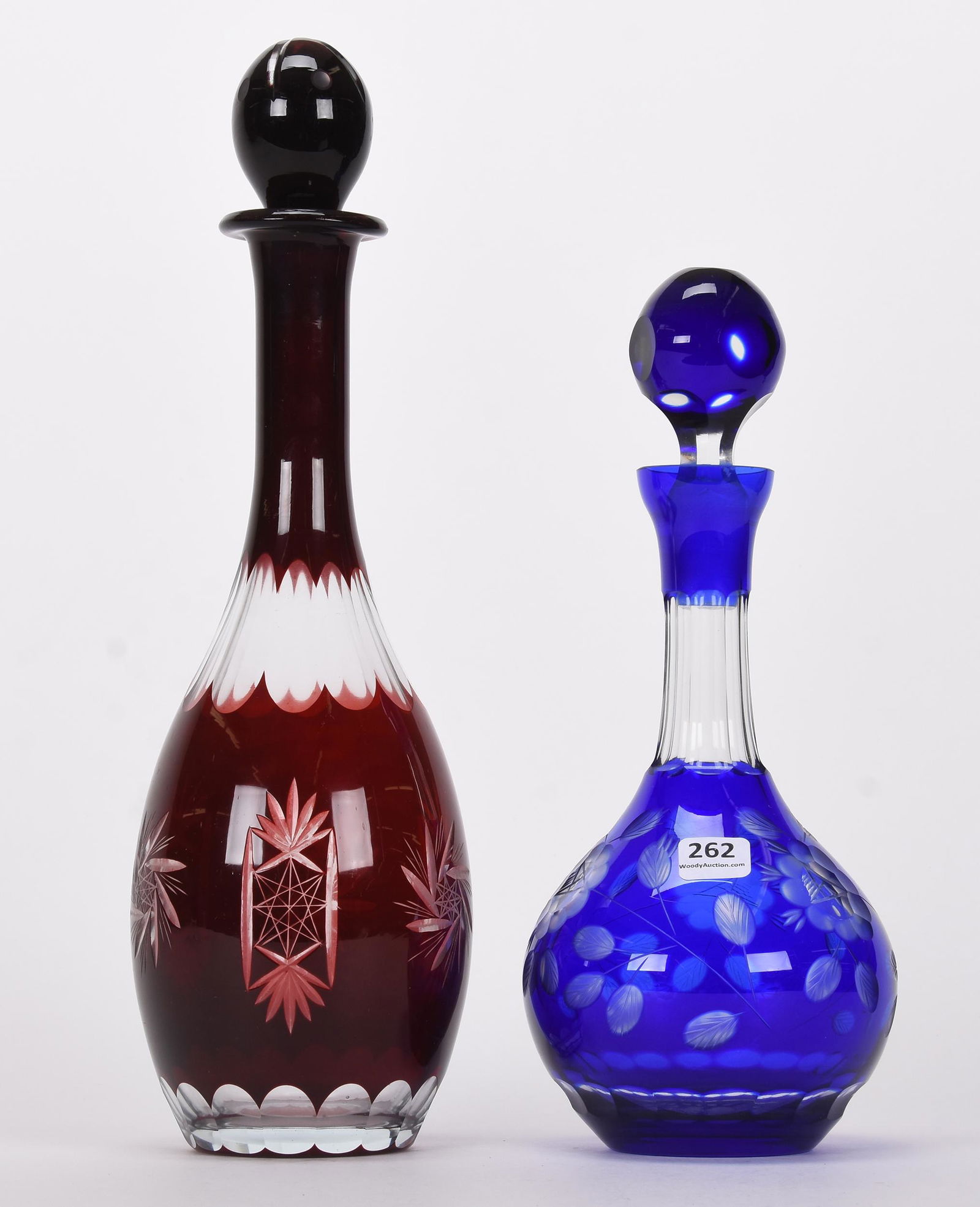 (2) Contemporary cut glass decanters: (2) Contemporary cut glass decanters; 14", 11" (1) 14" Ruby cut to clear, pinwheel and fan motif; (1) 11" Cobalt blue cut to clear, engraved floral motif; Hopper Collection, Kansas