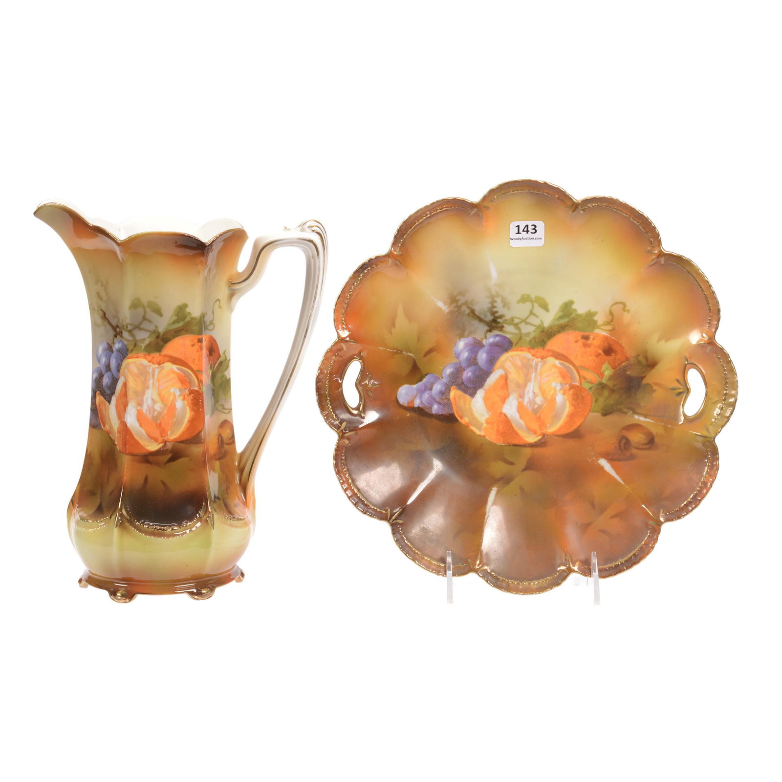 (2) Unmarked R.S. Prussia Items: (2) Unmarked R.S. Prussia Items, (1) 10.5" Cake Plate, Scallop Mold, Brown Tones with Fruit Decor, Some Rubbed Marks on Ridges, (1) 10" Tankard, Six-Sided, Brown Tones, Fruit Decor, Crow's Foot in Bas