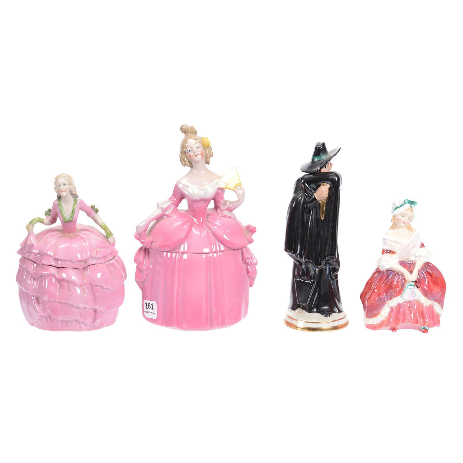 (4) Porcelain Figurines: (4) Porcelain Figurines, (1) 7.75", Covered Box in Form of Woman in Pink Dress, Unmarked, (1) 7" Guy Fawkes Figure, Black Cape and Hat, Attributed to Germany, Small Paint Flake on Bottom Edge of Cape,
