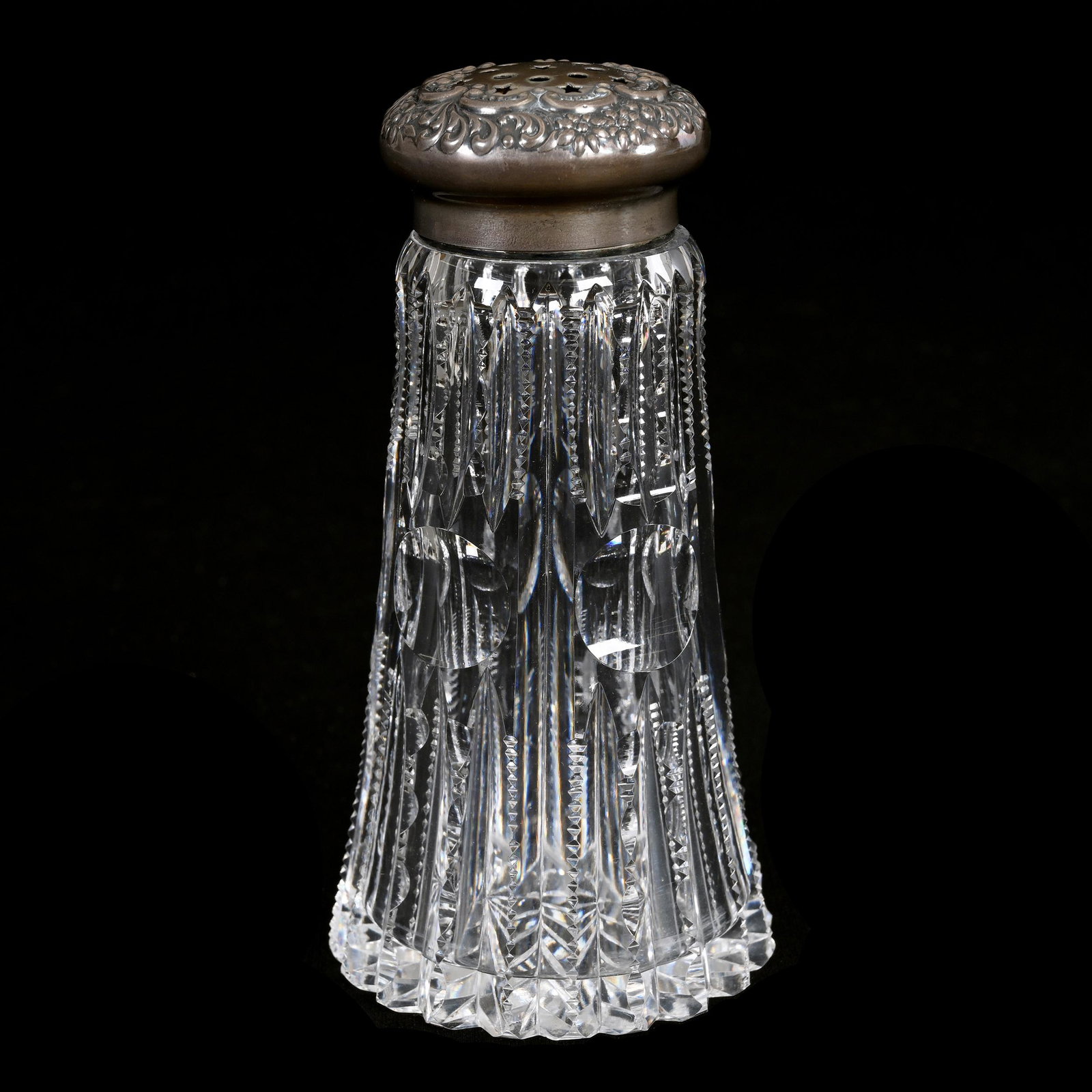 Sugar Shaker, American Brilliant Cut Glass: Sugar Shaker, American Brilliant Cut Glass, 5.5" x 2.75", Prism And Bullseye Pattern, Ray Cut Base, Sterling Silver Embossed Top Marked Wilcox, Base Chip, Estate Of Dr. Barry and Dee Free.
