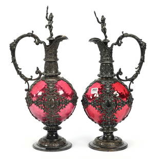 Pair Pedestal Decanters, Cranberry Art Glass Body: Pair Pedestal Decanters, Cranberry Art Glass Body, 15.5" x 7.5", Elaborate Embossed Silverplate Fittings, Full Figure Putti Stoppers, Nice Pair, These Items Sold In A Previous Woody Auction But Buyer