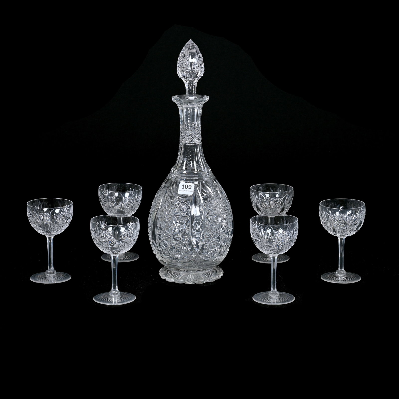 Decanter Set, ABCG, Grecian Pattern By Hawkes: Decanter Set, American Brilliant Cut Glass, Grecian Pattern By Hawkes, Pattern Cut Stopper, Scalloped Ray Cut Foot, (1) 14" x 5" Decanter, Minor Surface Rim Nick (6) Matching 4.5" x 2.5" Wine Stems, B