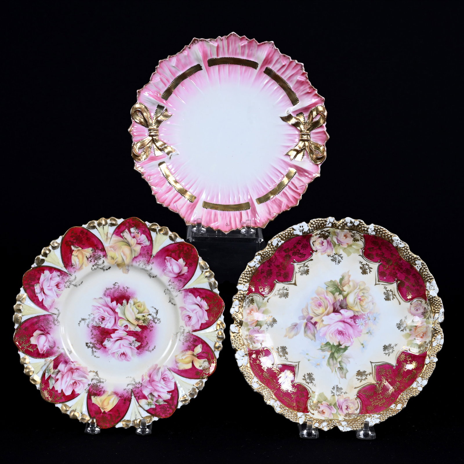 (3) Plates, Unmarked R. S. Prussia: (3) Plates, Unmarked R. S. Prussia, 8.5" approximately, (1) Stipple Mold, Cream With Red Border, Rose Decor, Crow's Foot On Back, (1) Cream And Red With Rose Decor, (1) Pink And White Bowtie Mold, Gol