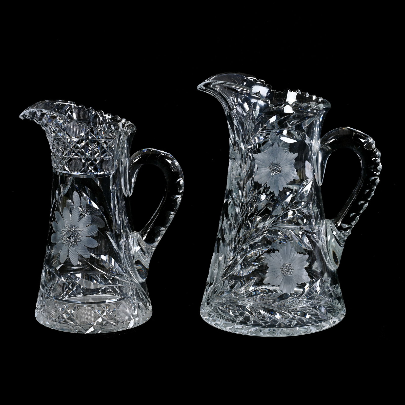 (2) Water Pitchers, ABCG: (2) Water Pitchers, American Brilliant Cut Glass, (1) 10.25" x 7.5", Engraved Floral Pattern, Triple Notched Handle, Hobstar Base, (1) 9" x 7", Harvard And Daisy Pattern, Ray Cut Base, Tooth Chip, Col
