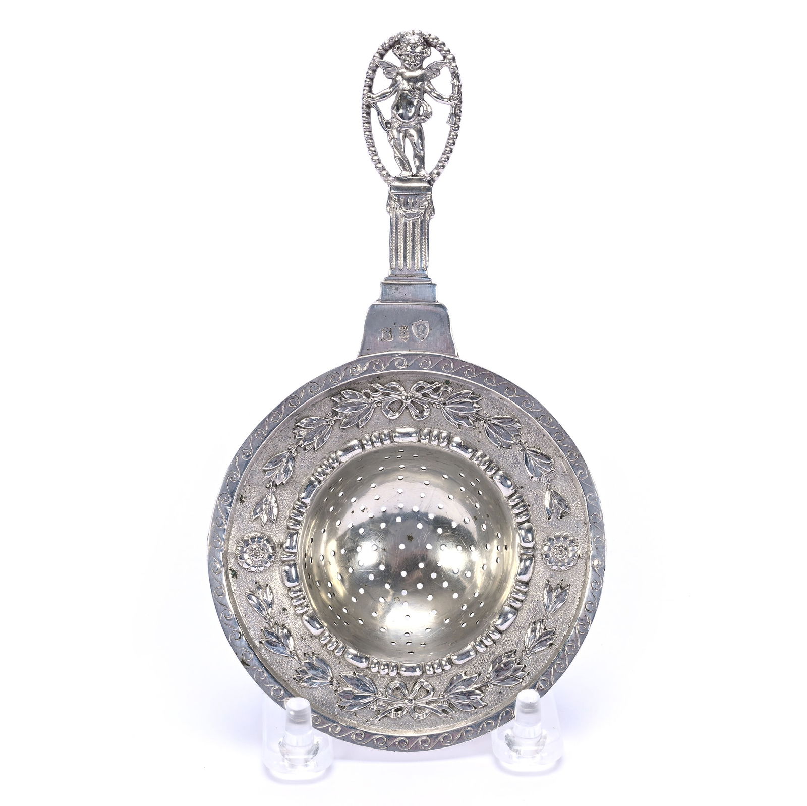 Solid Continental Silver Tea Strainer, Unidentified Hallmarks: Solid Continental Silver Tea Strainer, Unidentified Hallmarks, 6.25 x 3.5 x 3.5 Inches, Cherub Atop Pillar Surrounded By Cut-Out Medallion, 71.0 Grams, Dr. Harold & Audrey Eklund Estate, Iowa.