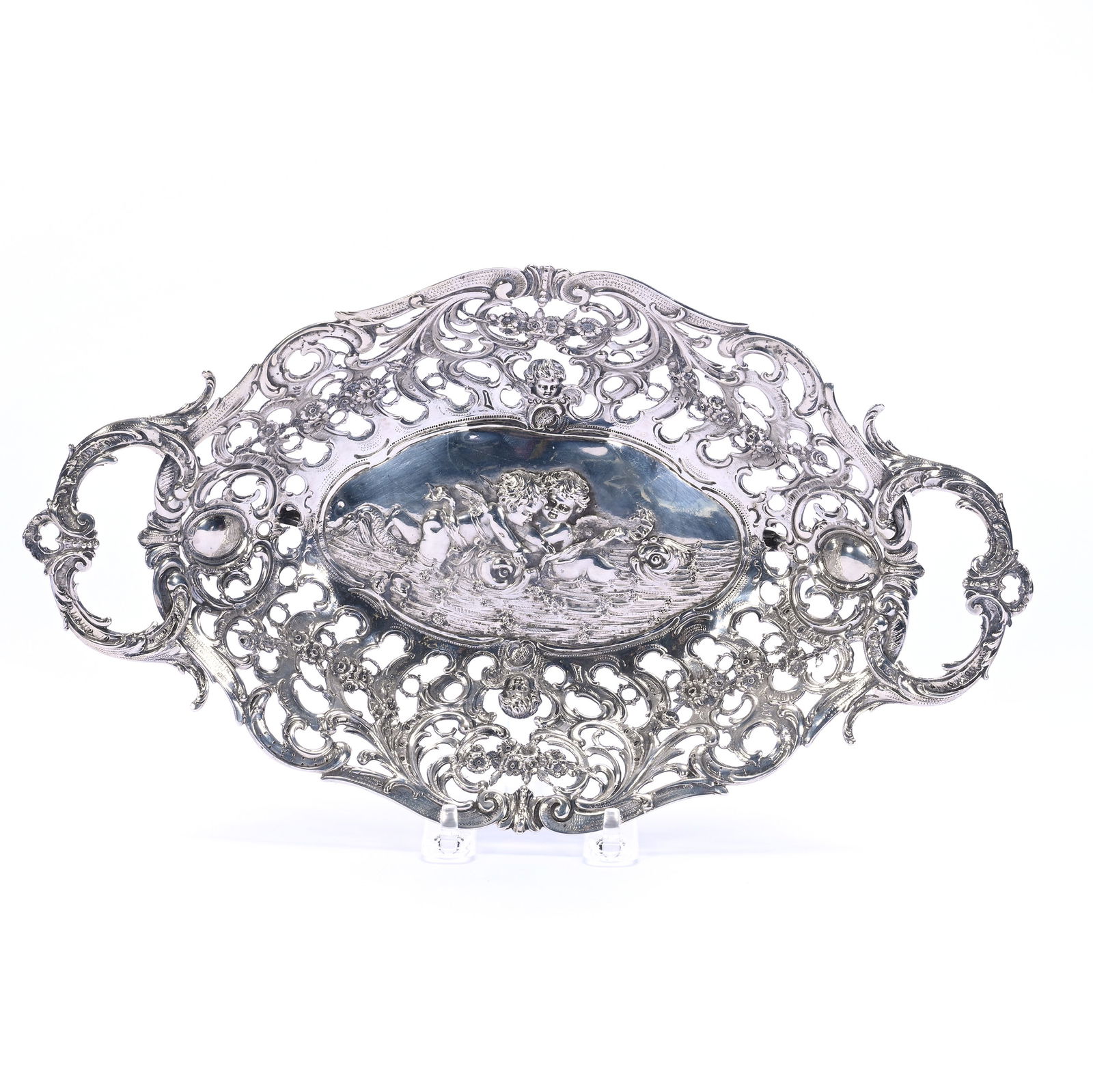 Solid German Silver Footed Bowl, Handled, Embossed Scene Of Cherubs Playing With Dolphins: Solid German Silver Footed Bowl, Handled, Embossed Scene Of Cherubs Playing With Dolphins, 2.75 x 13.5 x 7.75 Inches, Highly Reticulated Edge, 800 Purity, 423.0 Grams, Dr. Harold & Audrey Eklund Estat