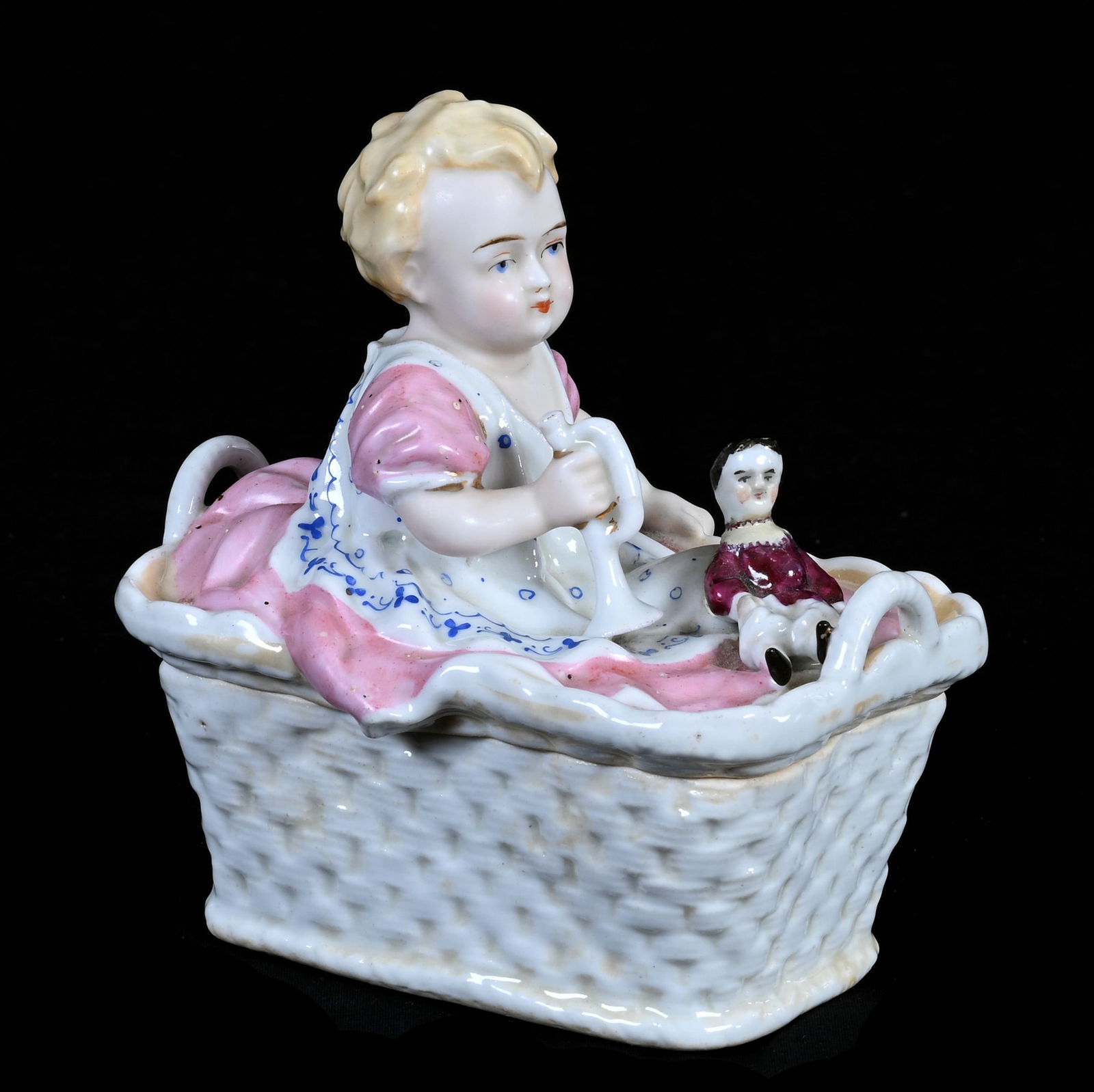 Figural Covered Box, Unmarked German Fairings Trinket Box: Figural Covered Box, Unmarked German Fairings Trinket Box, 5 x 4.75 x 3.75 Inches, Young Girl Sitting In Basket With Doll & Trumpet, Circa 1880's, 1.0 Pounds, Dr. Harold & Audrey Eklund Estate, Iowa.