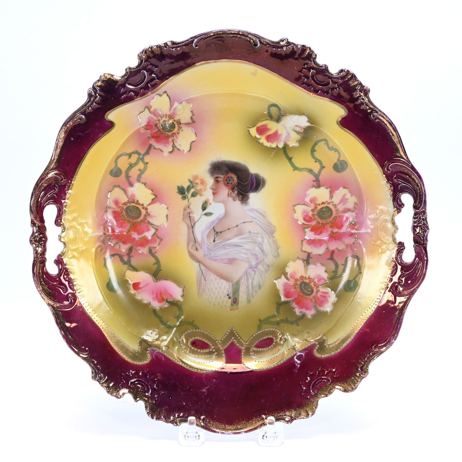Two Handled Cake Plate, Marked Prov Saxe: Two Handled Cake Plate, Marked Prov Saxe, 11 x 11.25 x 1.5 Inches, Yellow, Pink, And Green Background With Scene Of Woman Smelling Rose, Poppy Floral Highlights, Maroon Border, Base Ring Chip Polish,