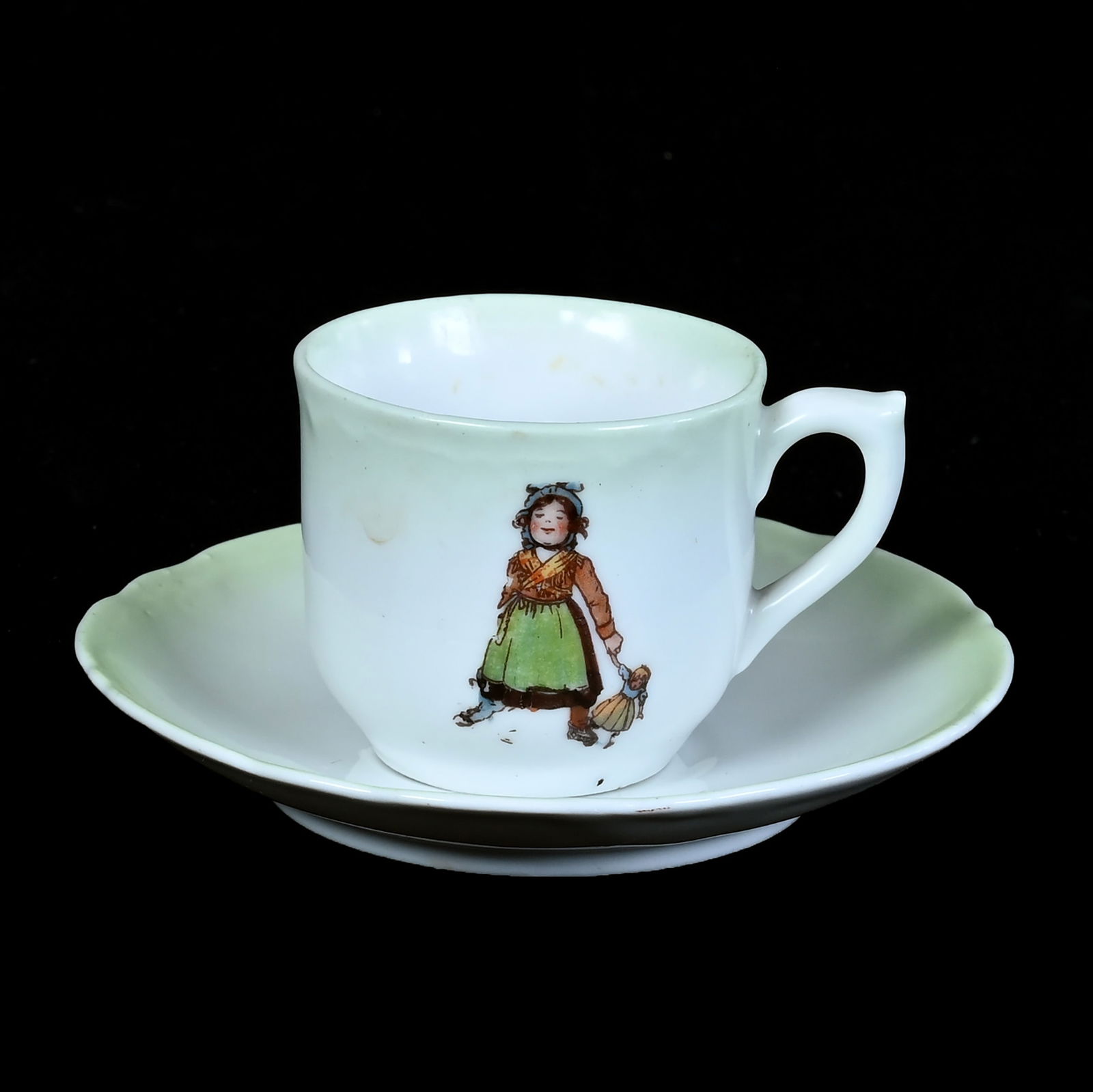 Child's Cup And Saucer, Marked German: Child's Cup And Saucer, Marked German, 2 x 4.25 x 4.25 Inches, Green And White With Scene Of Girl With Doll And Boy Hunting With Dog, 0.2 Pounds, Grady And Annette Hite Collection.