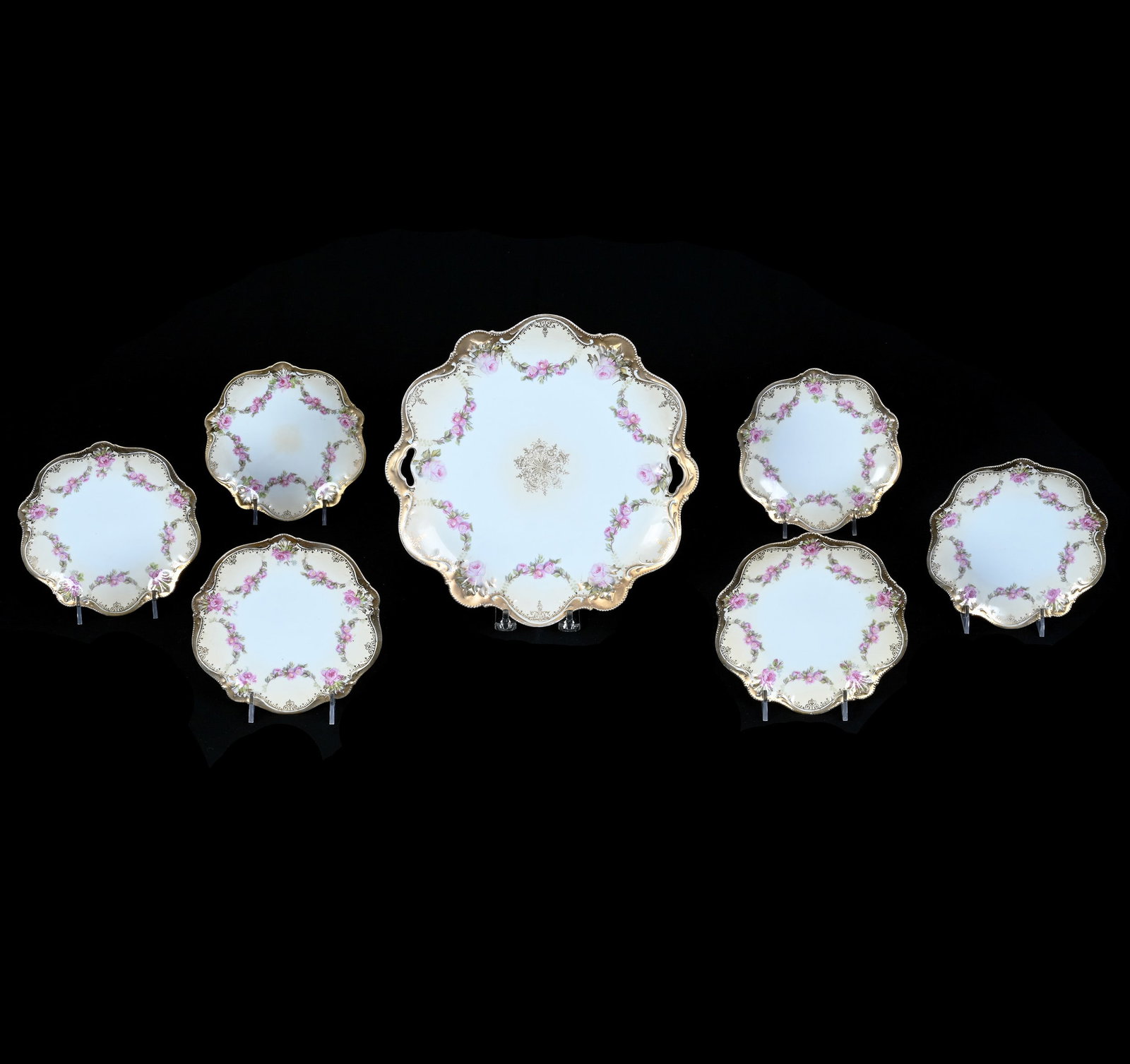 Cake Set, Marked R.S. Prussia: Cake Set, Marked R.S. Prussia, 10.75 x 10.75 x 1 Inches, White And Cream Tones With Pink Rose Garland Decor And Heavy Gold Trim With (6) 6.25" Cake Plates, 2.5 Pounds. LiveAuctioneers Invoices Must Be