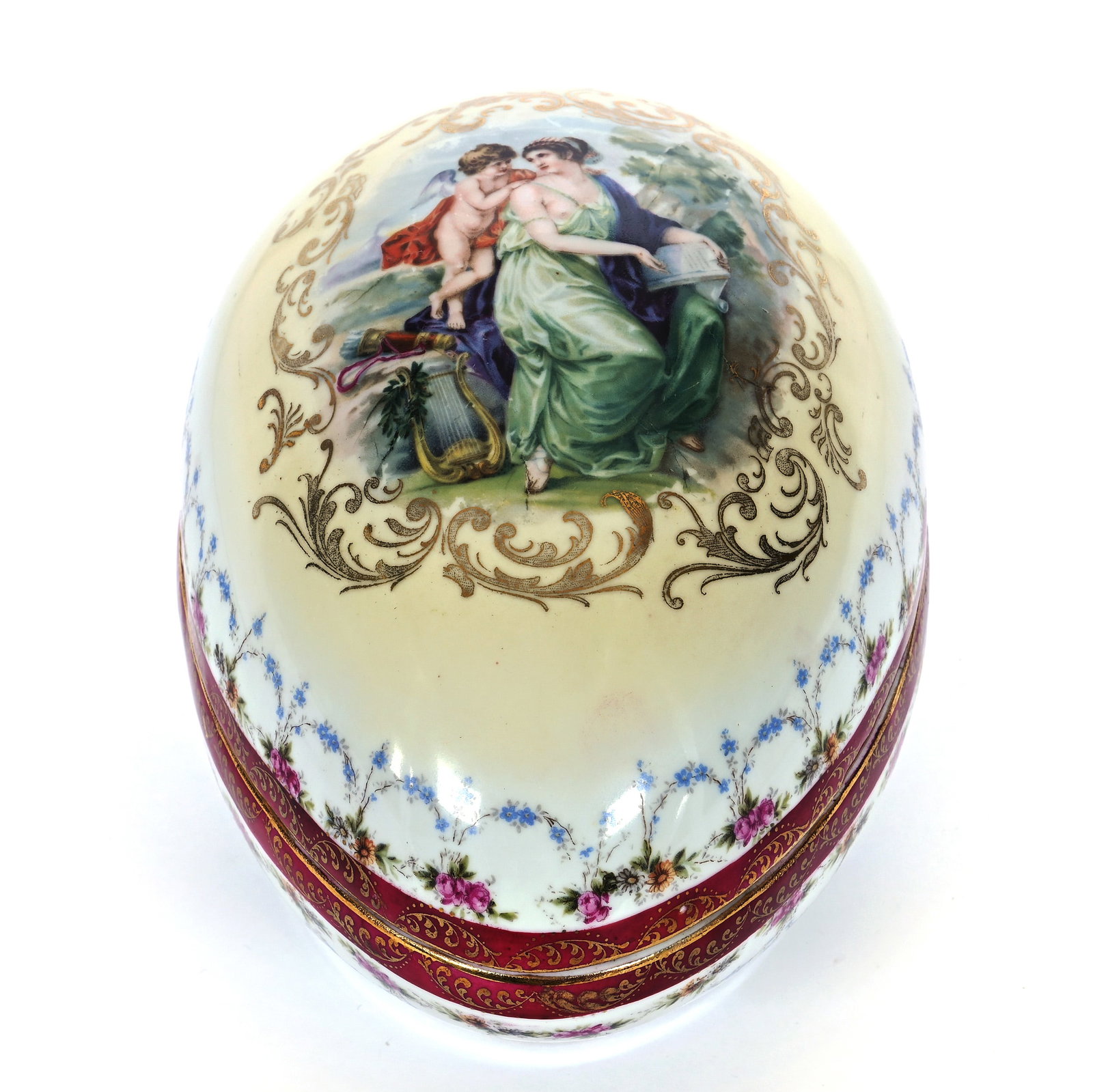 Egg Shaped Covered Box, Unmarked Prov Saxe: Egg Shaped Covered Box, Unmarked Prov Saxe, 5.25 x 7.5 x 5 Inches, Yellow And White Tones With Classic Woman And Cherub Scenic Decor, Maroon Border And Floral Garland Highlights, 1.8 Pounds.