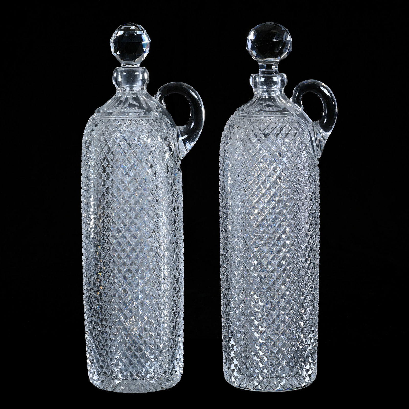 (2) Whiskey Bottles, Handled, American Brilliant Cut Glass, Full Crosscut Diamond Pattern: (2) Whiskey Bottles, Handled, American Brilliant Cut Glass, Full Crosscut Diamond Pattern, 13.75 x 4.25 x 3.75 Inches, Ray Cut Base, Stoppers Have Slightly Different Form, Both Are Well Fitted To Bott