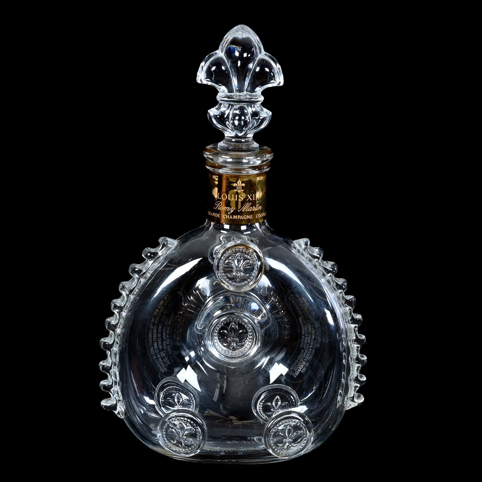 Cognac Bottle, Signed Baccarat Crystal: Cognac Bottle, Signed Baccarat Crystal, 11 x 6.75 x 3.5 Inches, Donut Shaped With Fleur De Lys Medallions, Louis XIII, Remy Martin Grande Champagne Cognac, Sells With 12.25? x 12.25? x 7" Original Box