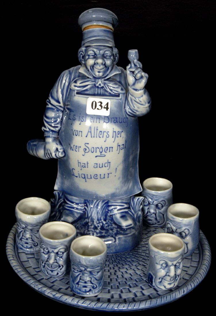8 PIECE MARKED SCHAFER AND VATER FIGURAL LIQUEUR SET: 8 PIECE MARKED SCHAFER AND VATER FIGURAL LIQUEUR SET 9 1/4" MAN HOLDING GLASS AND WEARING APRON WITH GERMAN SAYING "ES ISF CIN BRAUCH VON ALTERS HER, WE SORGEN HAF HAF AUCH LIQUEUR!" - INCLUDES SIX DO