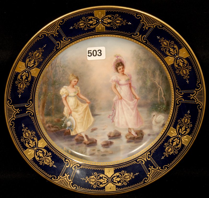 9 1/2" MARKED BEEHIVE SCENIC PLATE: 9 1/2" MARKED BEEHIVE SCENIC PLATE COBALT BLUE BORDER WITH GOLD HIGHLIGHTS - SCENE FEATURES TWO WOMEN CROSSING CREEK ON STEPPING STONES - TITLED "WIE NUN WEITER?" WHICH TRANSLATES TO "WHAT NOW?" - ART