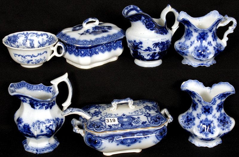 (7) FLOW BLUE ITEMS: INCLUDES (3) CREAMERS - (1) SYRIAN PATTERN SPOONER (SMALL CHIP) - (1) COVERED SOAP DISH - (1) DEVON PATTERN COVERED SAUCE - (1) CUP