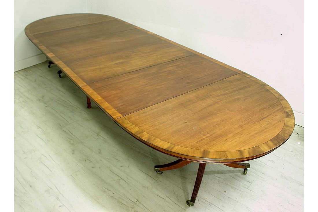 Antique Walnut Dining Table: Antique English banded walnut twin pedestal dining table of oval outline with 4 extension leaves on castered pedestal supports. Circa 1920. Total length approx. 115" width approx. 57".