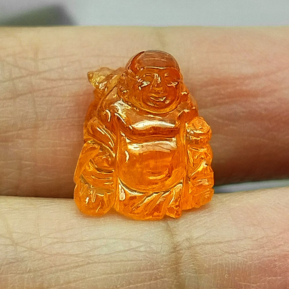 Orange Spessartine Garnet 14.95 Ct. Carving Happy Buddha Shape 12.5 x 15.5 Mm. Natural Gemstone: Product ID: 501200049 Product Name: Natural Spessartine Garnet Weight: 14.95 CT. Size: 12.5 x 15.5 x 11 MM. Shape: Carving Color: Orange Natural Clarity:None Luster: Good Gems Origin: Namibia Treatmen