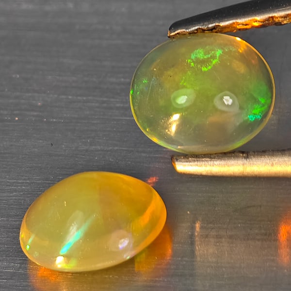 Natural Multi Color Play Of Colour Opal 0.97 Ct. 2 Pcs Oval Cabochon Shape Gemstones From Ethiopia: Product ID: 818728364 Product Name: Natural Opal Weight: 0.97 CT. Size: 6.4 x 5.6 x 3 MM. Shape: Oval Cabochon Color: Multi-Color Clarity:None Luster: Good Gems Origin: Ethiopia Treatment: Unheated