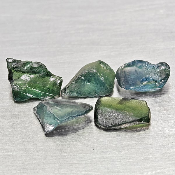 Natural Greenish Blue Sapphire Gemstones 3.94 Ct. 5 Pcs. Rough Shape: Product ID: 806162539 Product Name: Natural Green Sapphire Weight: 3.94 CT. Size: 7 x 4.7 x 2.5 to 6.1 x 5.6 x 3.2 MM. Shape: Rough Mixed Shape Color: Greenish Blue Clarity:VSI Luster: Good Gems Origi