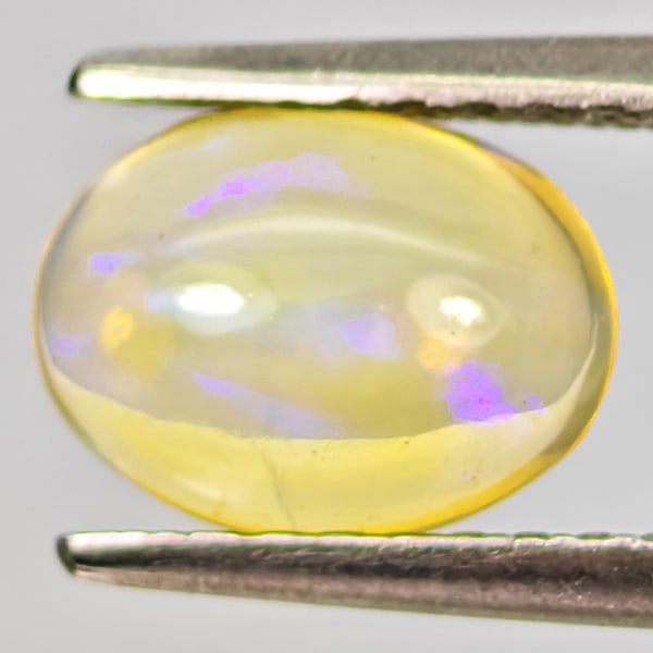 Natural Multi-Color Play Of Colour Opal 0.67 Ct. Oval Cabochon Shape 7.9 x 5.9 Mm.: Product ID: 818728057 Product Name: Natural Opal Weight: 0.67 CT. Size: 7.9 x 5.9 x 3.3 MM. Shape: Oval Cabochon Color: Multi-Color Clarity:Semi - Transparent Luster: Good Gems Origin: Ethiopia Treatm