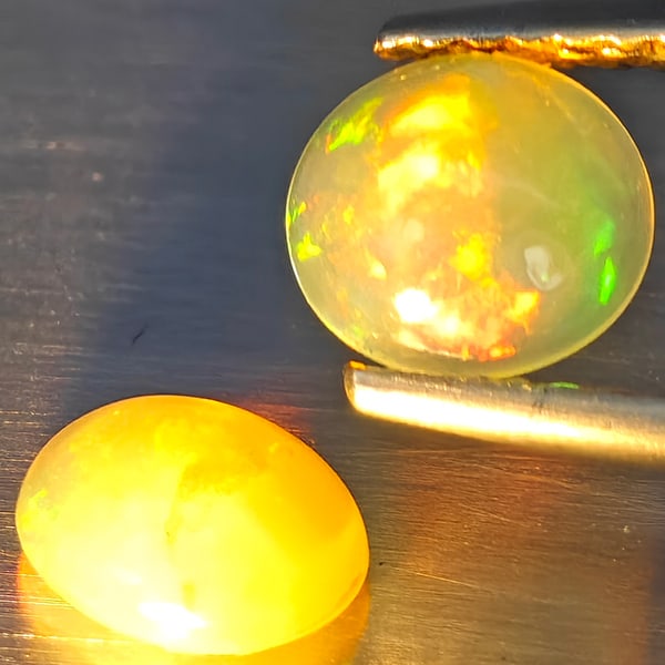 Natural Multi-Color Play Of Colour Opal Gemstones 0.87 Ct. 2 Pcs. Oval Cabochon Shape 6.4 x 5.9 Mm.: Product ID: 818728325 Product Name: Natural Opal Weight: 0.87 CT. Size: 6.4 x 5.9 x 2.6 MM. Shape: Oval Cabochon Color: Multi-Color Clarity:None Luster: Good Gems Origin: Ethiopia Treatment: Unheated 