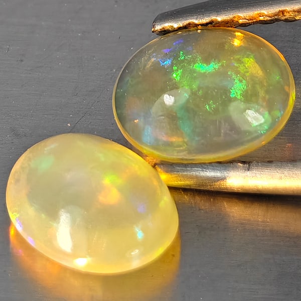 Natural Multi-Color Play Of Colour Opal Gemstones 0.91 Ct. 2 Pcs. Oval Cabochon Shape 7 x 5.6 Mm.: Product ID: 818728284 Product Name: Natural Opal Weight: 0.91 CT. Size: 7 x 5.6 x 3.4 MM. Shape: Oval Cabochon Color: Multi-Color Clarity:None Luster: Good Gems Origin: Ethiopia Treatment: Unheated Cr