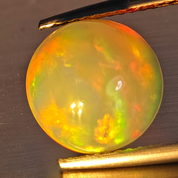 Natural Multi-Color Opal Gemstone 3.78 Ct. Round Cabochon Shape 10.3 Mm.: Product ID: 708700123 Product Name: Natural Opal Weight: 3.78 CT. Size: 10.3 x 10.3 x 6.1 MM. Shape: Round Cabochon Color: Multi-Color Clarity:Opaque Luster: Strong Iridescent Gems Origin: Ethiopia Tr