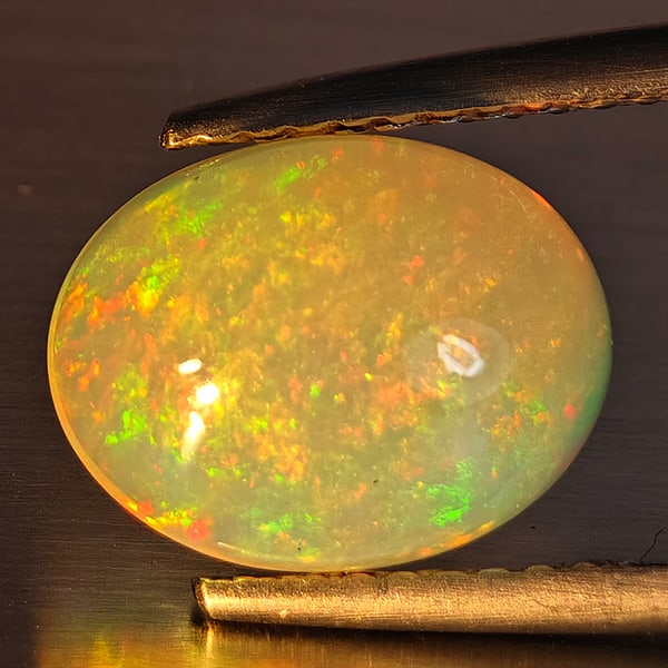 Natural Multi-Color Play Of Colour Opal Gemstone 3.26 Ct. Oval Cabochon Shape 12 x 9.4 Mm.: Product ID: 708700133 Product Name: Natural Opal Weight: 3.26 CT. Size: 12 x 9.4 x 6.5 MM. Shape: Oval Cabochon Color: Multi-Color Clarity:Opaque Luster: Strong Iridescent Gems Origin: Ethiopia Treatm