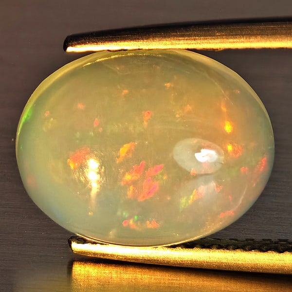 Natural Multi-Color Play Of Colour Opal Gemstone 3.22 Ct. Oval Cabochon Shape 14.2 x 10.1 Mm.: Product ID: 708700006 Product Name: Natural Opal Weight: 3.22 CT. Size: 14.2 x 10.1 x 4.7 MM. Shape: Oval Cabochon Color: Multi-Color Clarity:Opaque Luster: Good Gems Origin: Ethiopia Treatment: Unhea